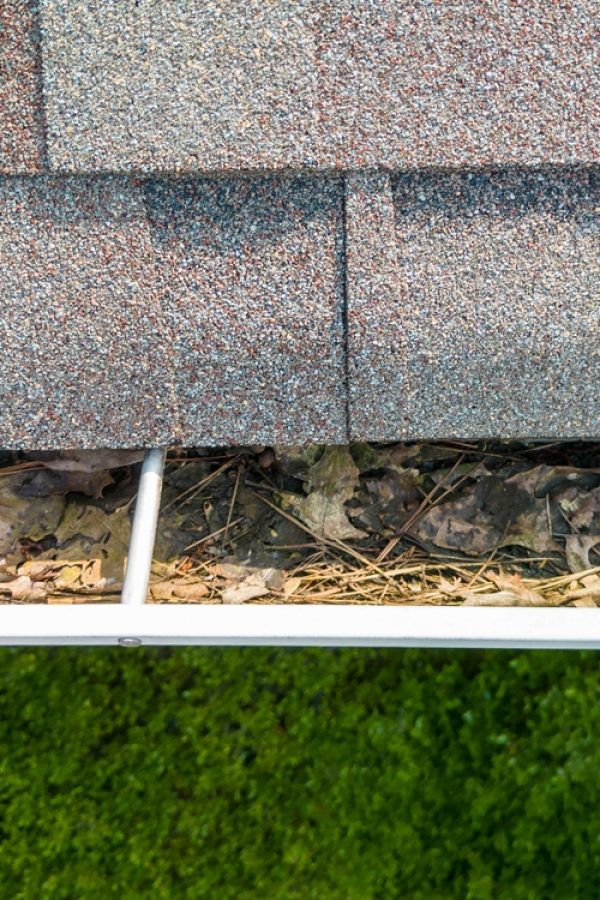 Metal,Gutters,Clogged,With,Leaves,And,Debris,On,A,Red